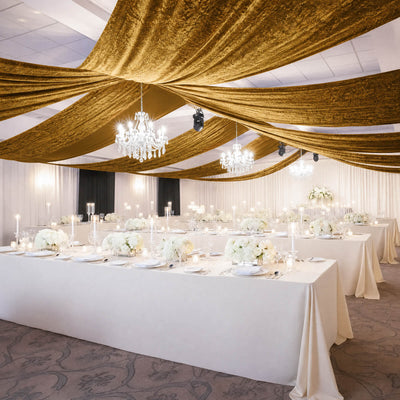 Elegant wedding reception with gold ceiling draping, chandeliers, and white tables