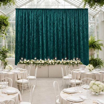 Elegant wedding reception with teal velvet backdrop, white florals, and round tables