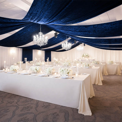 Elegant wedding reception with navy draped ceiling, chandeliers, and white floral tables