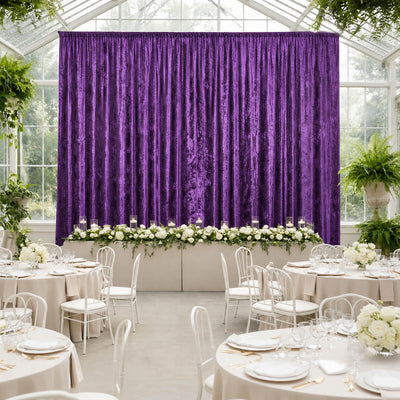 Elegant wedding reception with purple velvet backdrop, white florals, and round tables