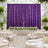 Elegant wedding reception with purple velvet backdrop, white florals, and round tables