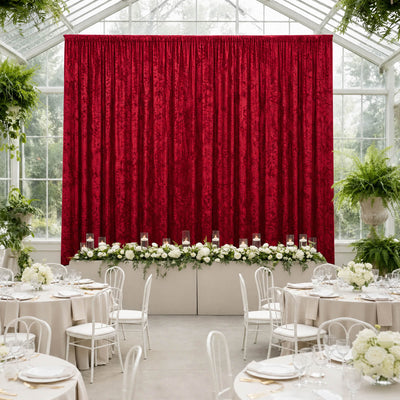 Elegant wedding reception with red velvet backdrop and white floral table decor