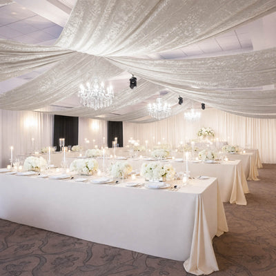 Elegant white wedding reception with chandeliers and floral tablescape