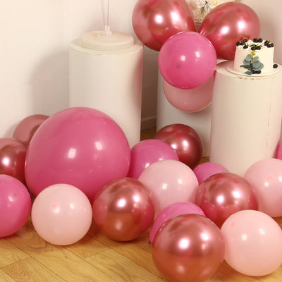 Assorted pink balloons scattered on a wooden floor.