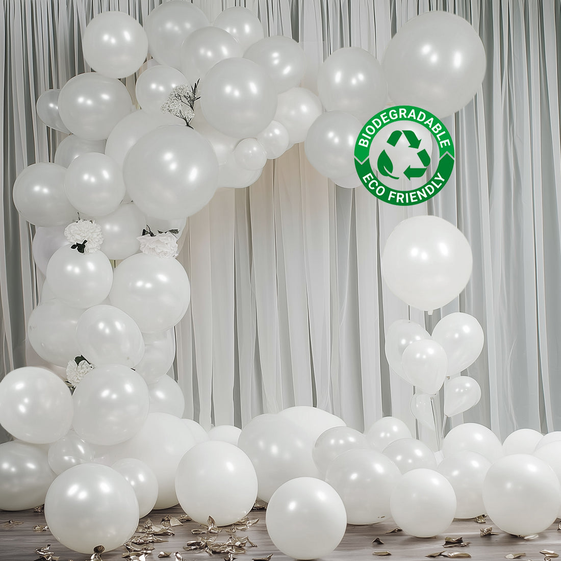 White biodegradable balloons forming a decorative arch with scattered balloons on the floor.