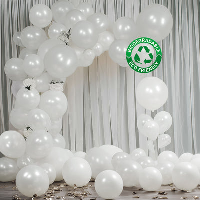 White biodegradable balloons forming a decorative arch with scattered balloons on the floor.