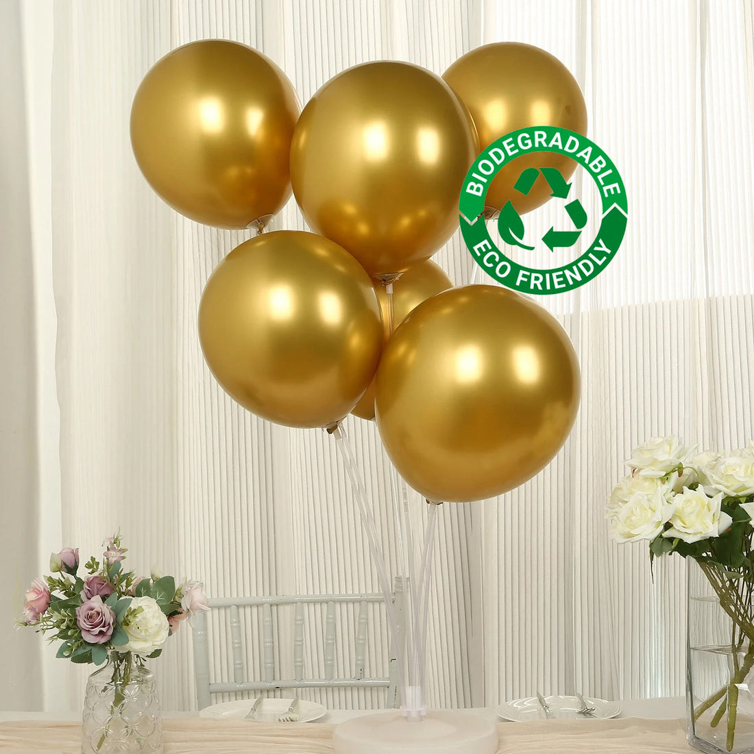 Gold biodegradable balloons arranged in a clear vase with flowers.