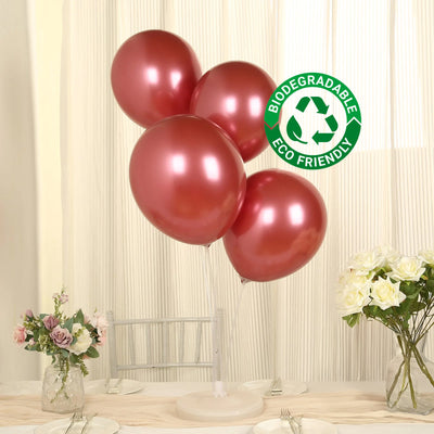 Set of four biodegradable rose gold balloons on a table with flowers.