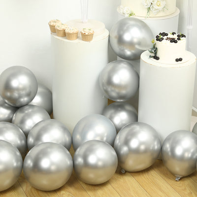 Silver balloons at a festive event with decorative cake and cupcakes.