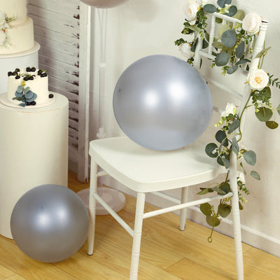Silver balloons on a white chair adorned with greenery and floral accents.