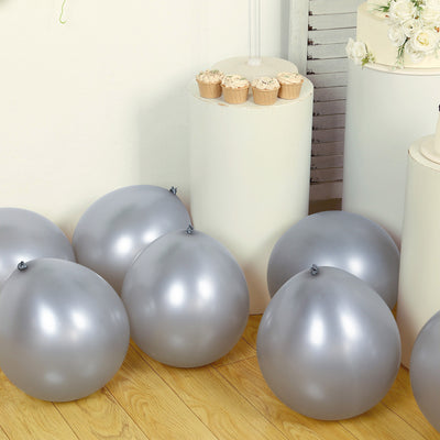 Silver balloons on a wooden floor near cupcakes in a minimalist setting.