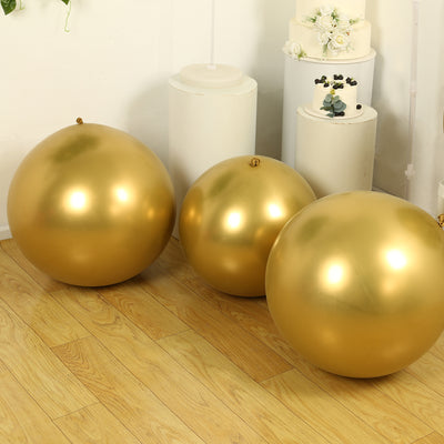 Three golden decorative balls on a wooden floor.