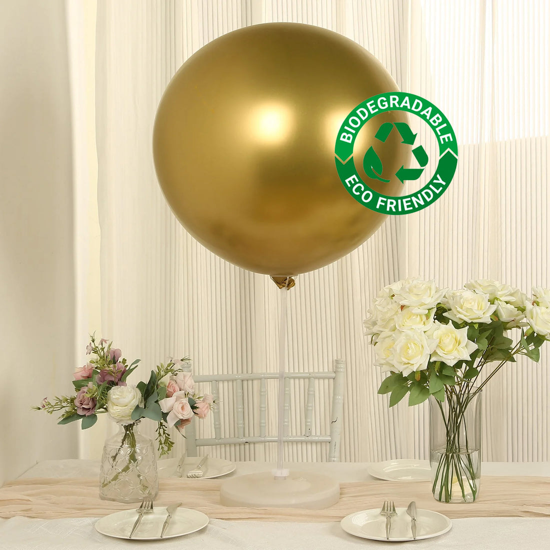 Gold biodegradable balloon on a table with flowers and dinnerware.