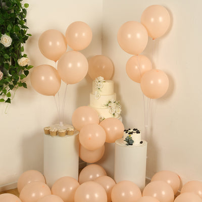 Peach balloons and a white cake with flowers in an elegant party setup.