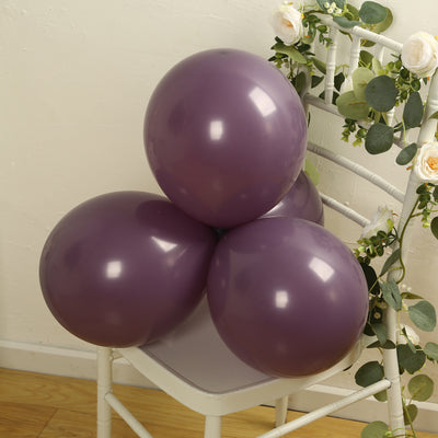 Purple balloons arranged on a white chair with greenery.