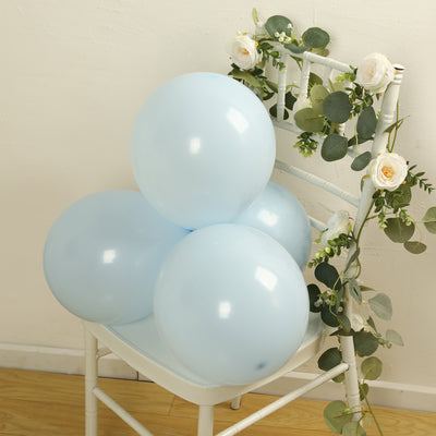 Light blue balloons arranged on a white chair with greenery and floral accents.