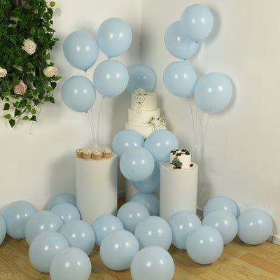 Light blue balloons with a cake and cupcakes in a decorated setting.