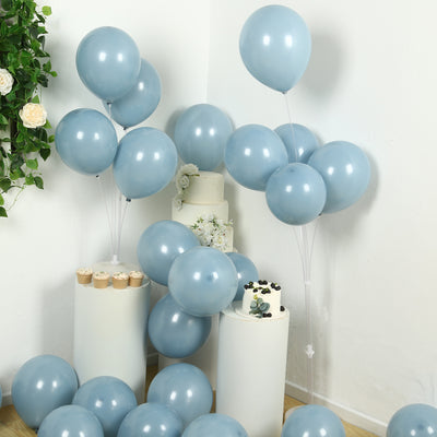 Light blue balloons arranged around cakes and cupcakes in a festive setting.
