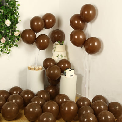 Brown balloons in a decorated setup with a cake and cupcakes.