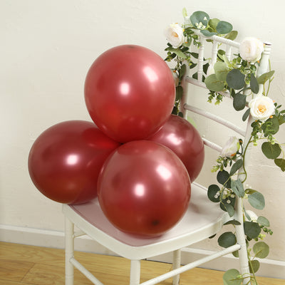 Red balloons resting on a white chair adorned with greenery.