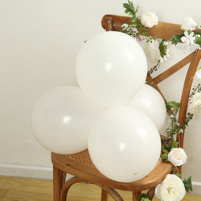 White balloons arranged on a wooden chair with floral decor.
