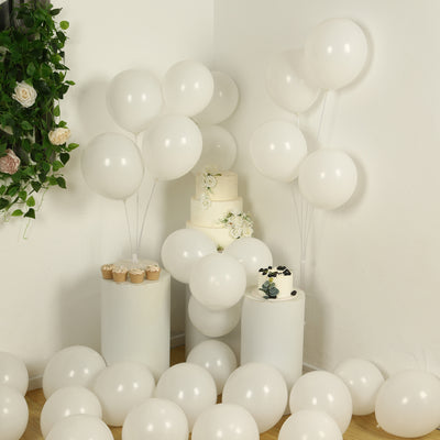 White balloons and cakes in a festive setting with floral accents.