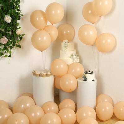 Peach balloons arranged around a cake and cupcakes in a festive setting.