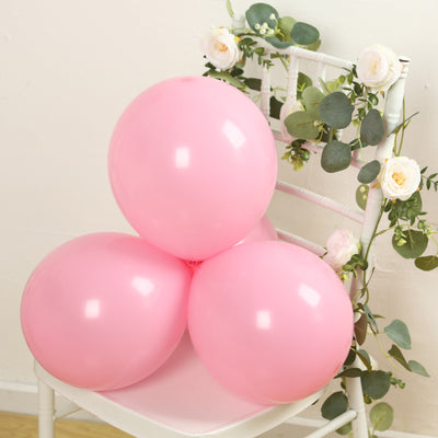 Pink balloons arranged on a chair with greenery and flowers.