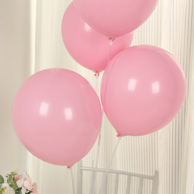 Four pink balloons floating indoors.