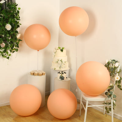 Peach balloons in a festive setup with a wedding cake and greenery.