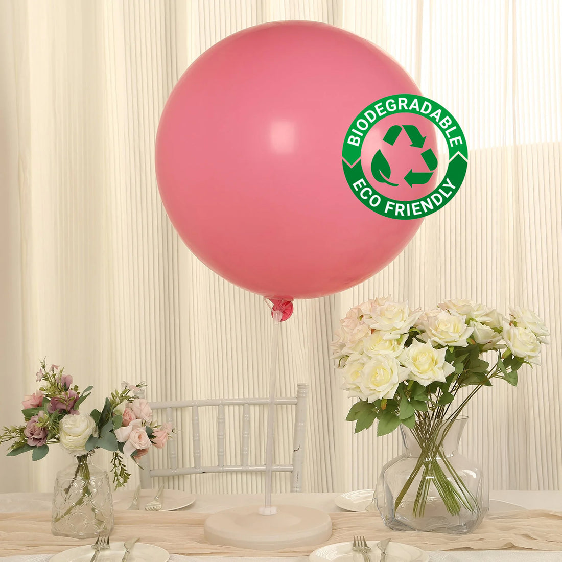 Pink biodegradable balloon with eco-friendly label on a decorated table.
