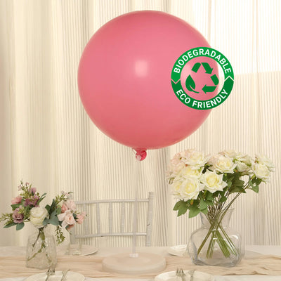 Pink biodegradable balloon with eco-friendly label on a decorated table.