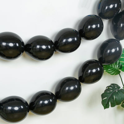 Black balloons arranged in a decorative garland against a white wall.