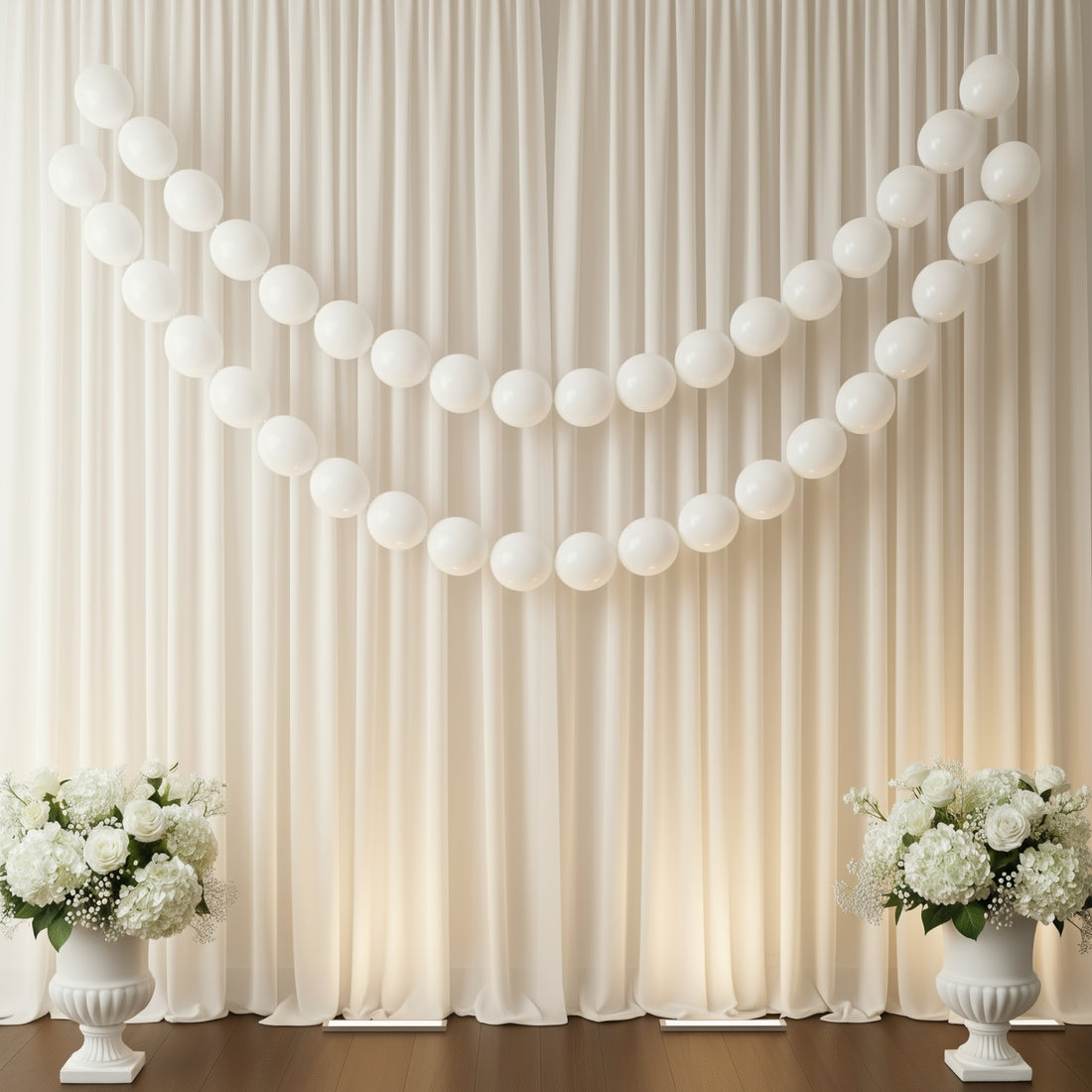 White balloons arranged in a decorative display with floral arrangements on either side.
