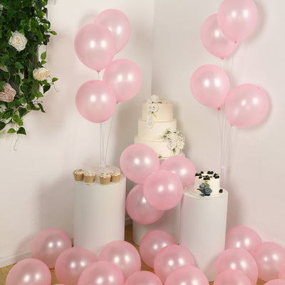 Pink balloons and a white cake with floral decorations in a festive setting.