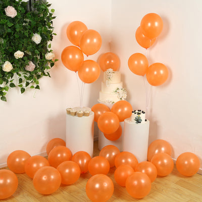 Orange balloons with a cake and cupcakes at a celebration setting.