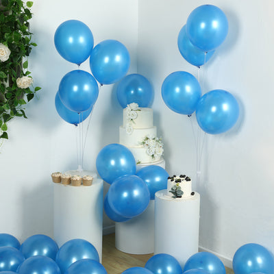 Blue balloons in a festive setup with a cake and cupcakes on display.