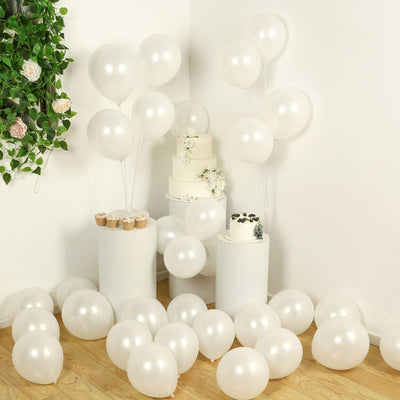 White balloons surrounding cakes and cupcakes in a festive setup.