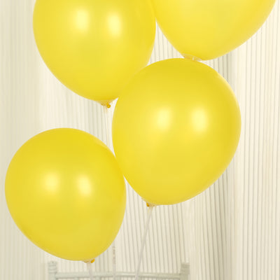 Four glossy yellow balloons floating together.