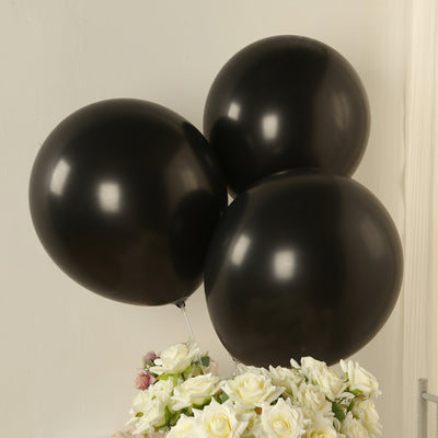 Three black balloons floating above a bouquet of white roses.