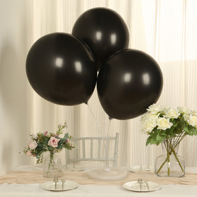 Three black balloons arranged on a table with floral centerpieces.