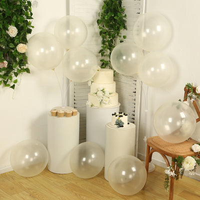 Clear balloons arranged with cakes and floral decor in a styled celebration scene.