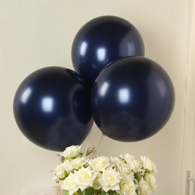 Three navy blue balloons floating above a bouquet of white roses.