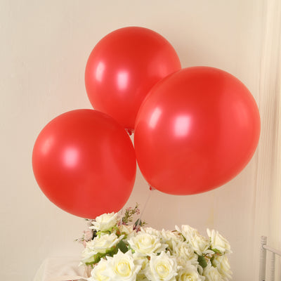 Three shiny red balloons above a bouquet of white roses.