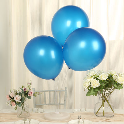 Three shiny blue balloons on a dining table with flowers and decor.