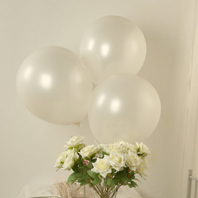 Three elegant white balloons beside a bouquet of white roses.