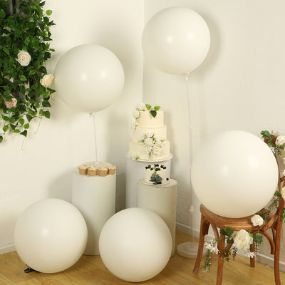 White balloons and cake displayed in a styled setting with floral accents.