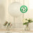 Large white biodegradable balloon on a table with flowers and dinnerware.