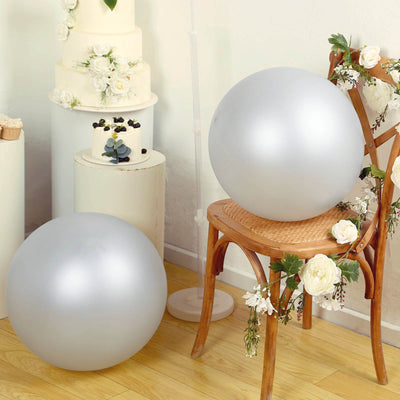 Silver decorative balls on a chair surrounded by flowers and cakes.