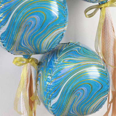 Swirled blue and gold balloons with ribbons hanging decoratively.